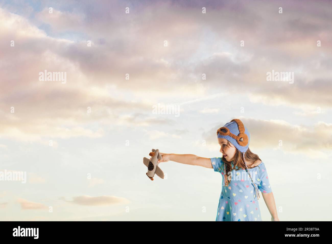Affascinato ragazza con un aeroplano giocattolo di immaginare il suo futuro professione Foto Stock