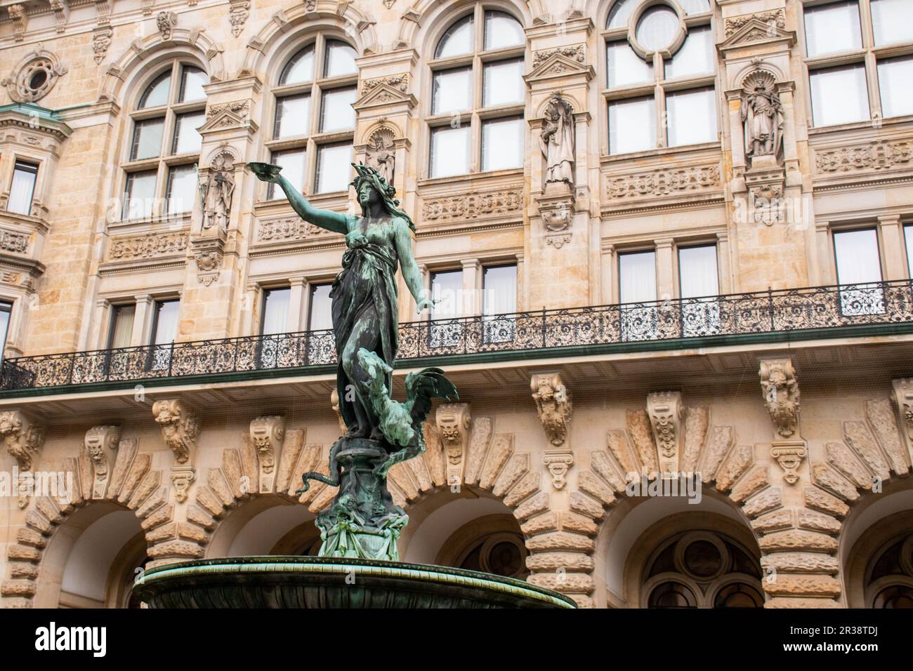 Particolare della statua ornata di Donna in fontana con grande antico edificio dietro Foto Stock