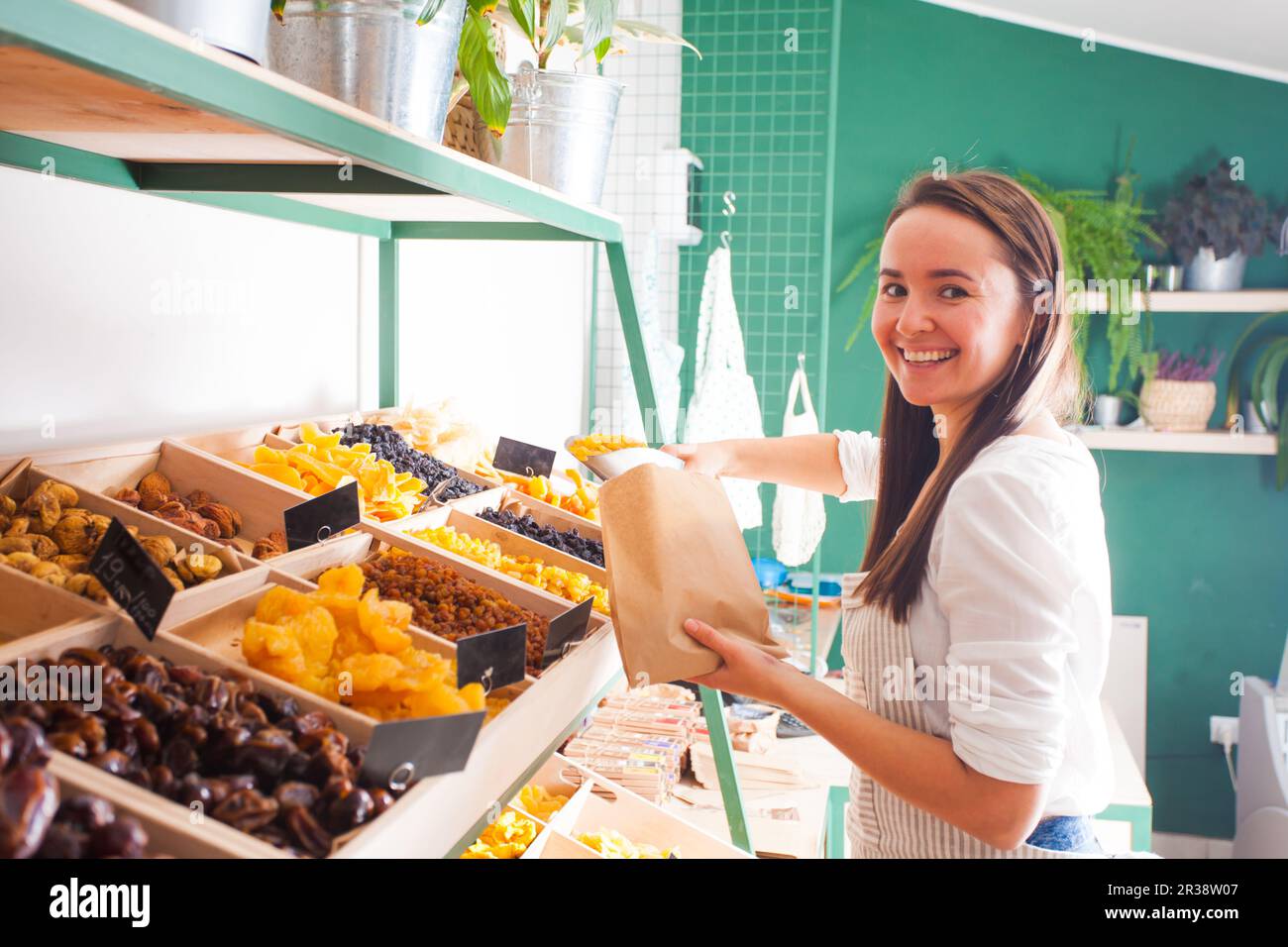 Giovane donna venditore confezioni frutta secca nel negozio di alimentari Foto Stock