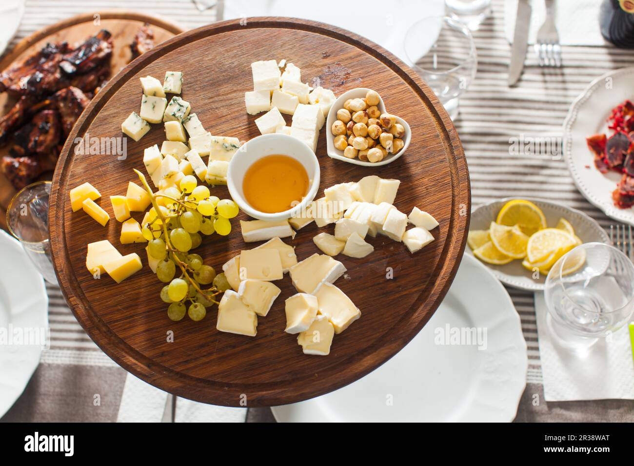 Il piatto di formaggi con nocciole, miele, uva sulla tavola di legno Foto Stock