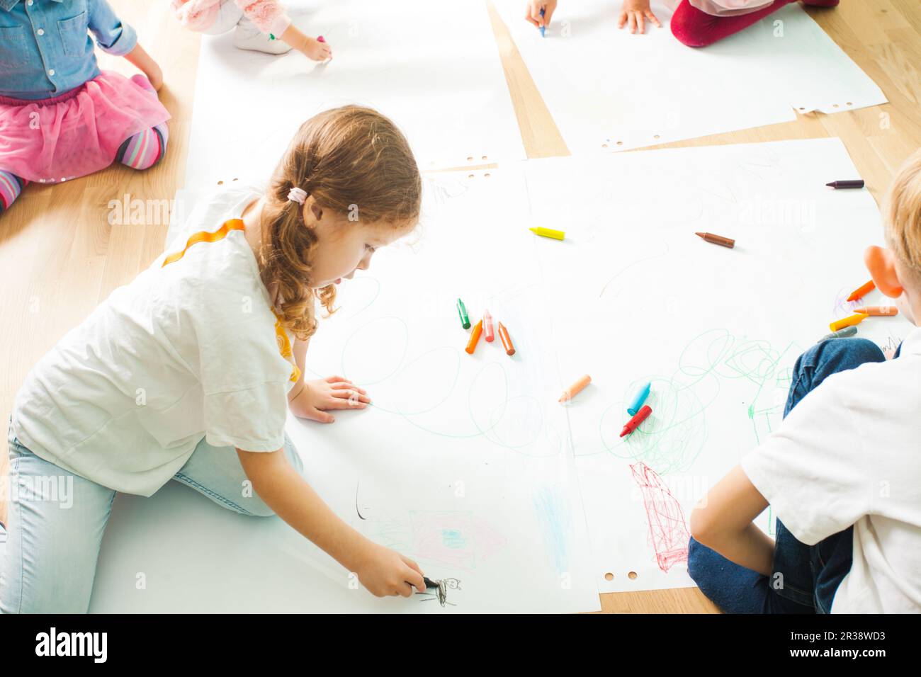 I bambini di Disegno con matite colorate su di un pavimento in legno Foto Stock