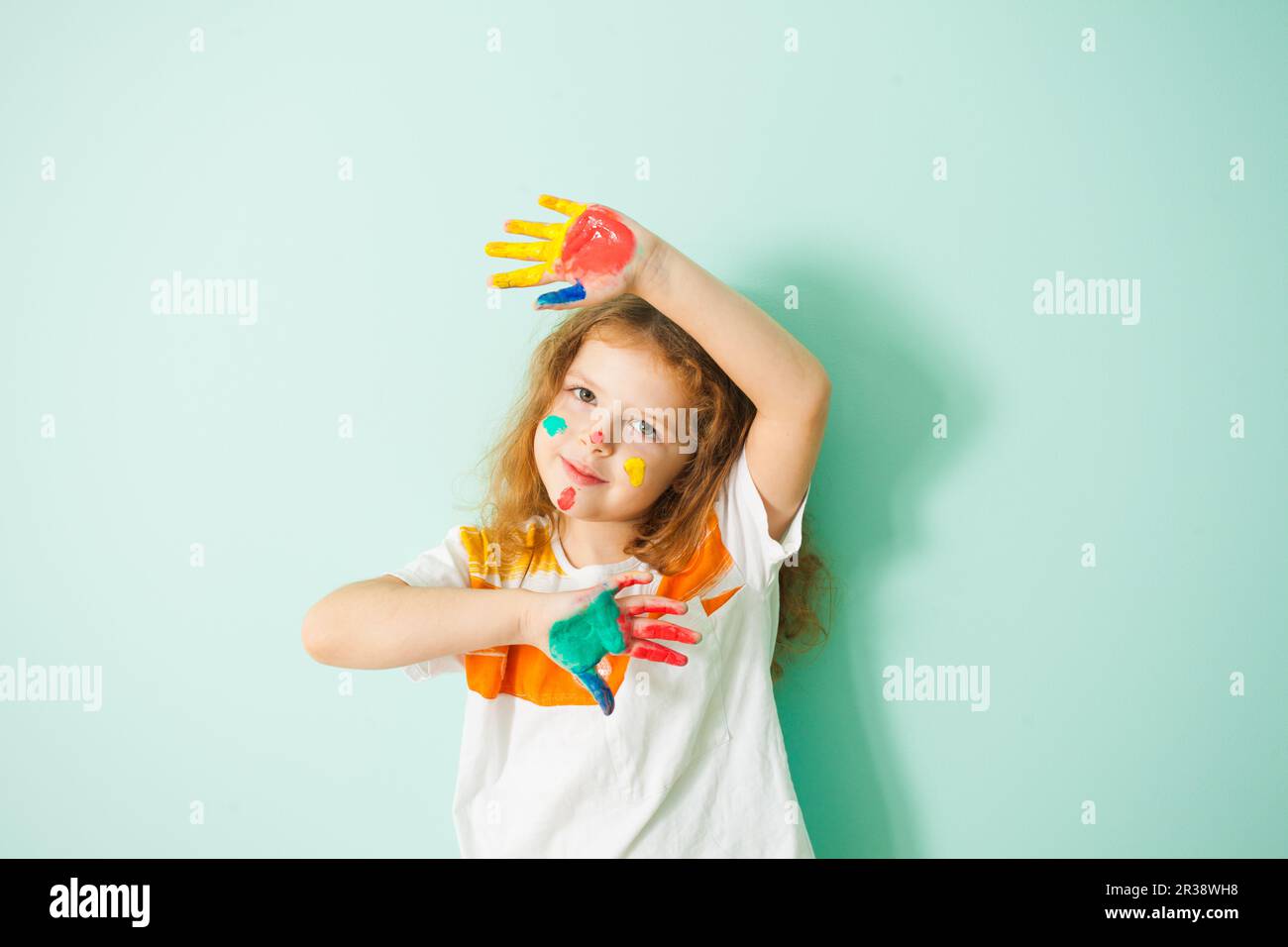 Bambina con le mani e il viso in paint Foto Stock