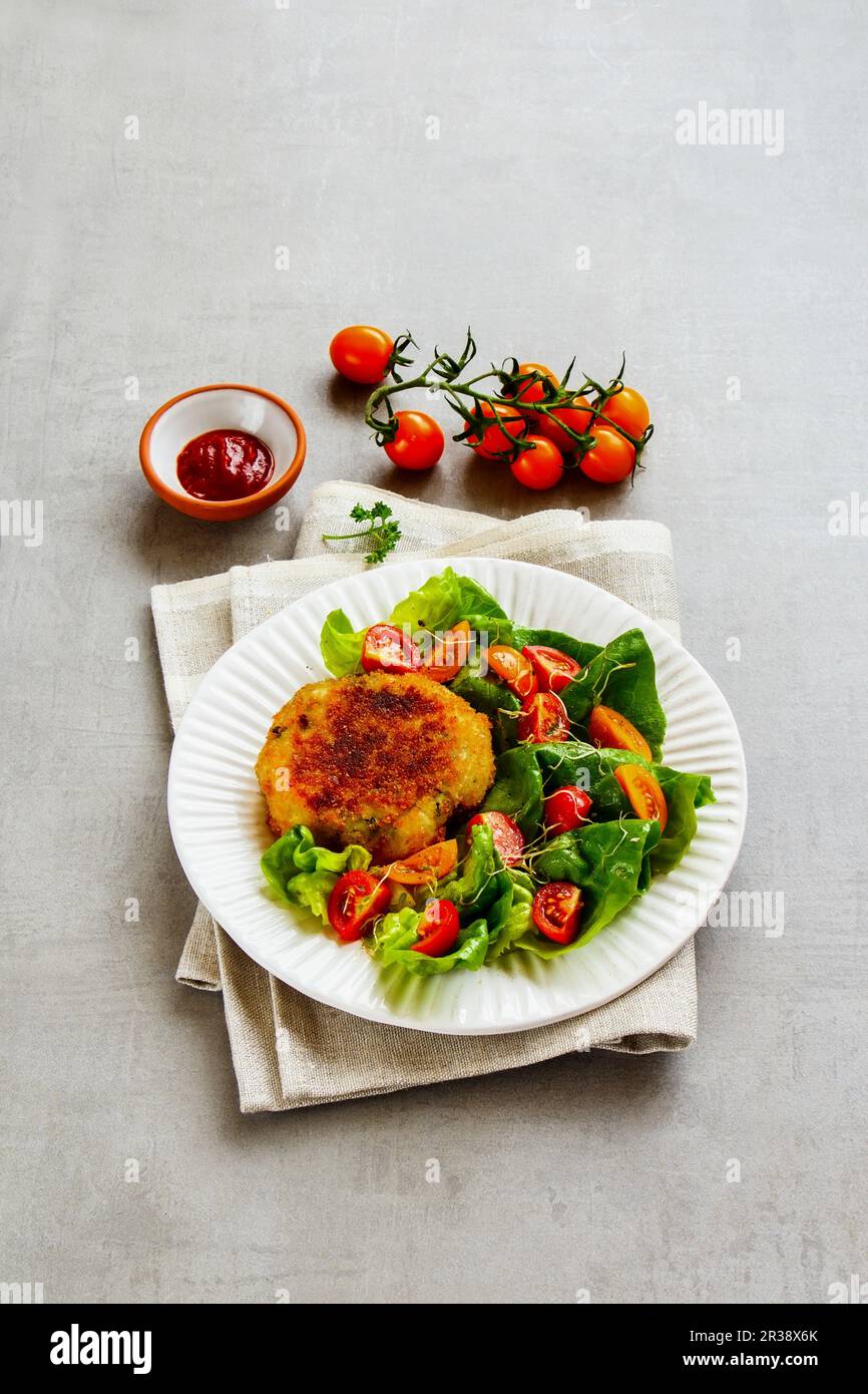 Frittelle di verdure vegane con insalata mista a foglie e pomodori Foto Stock