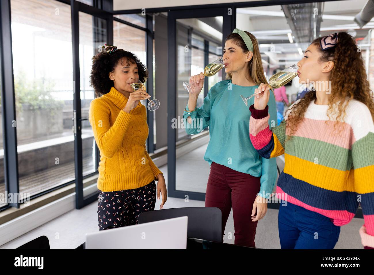 Felice gente d'affari diversi che festeggia e beve champagne in ufficio, inalterato Foto Stock