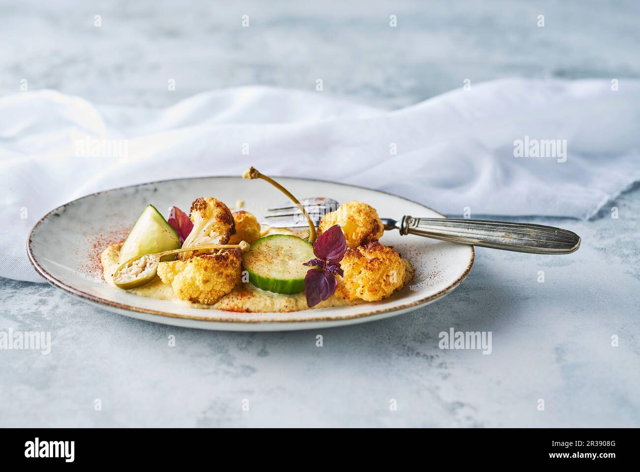 Cavolfiore arrosto con purea di cavolfiore di mandorle con cetriolo sottaceto, capperi di mele, cipolline e cress rosso Foto Stock