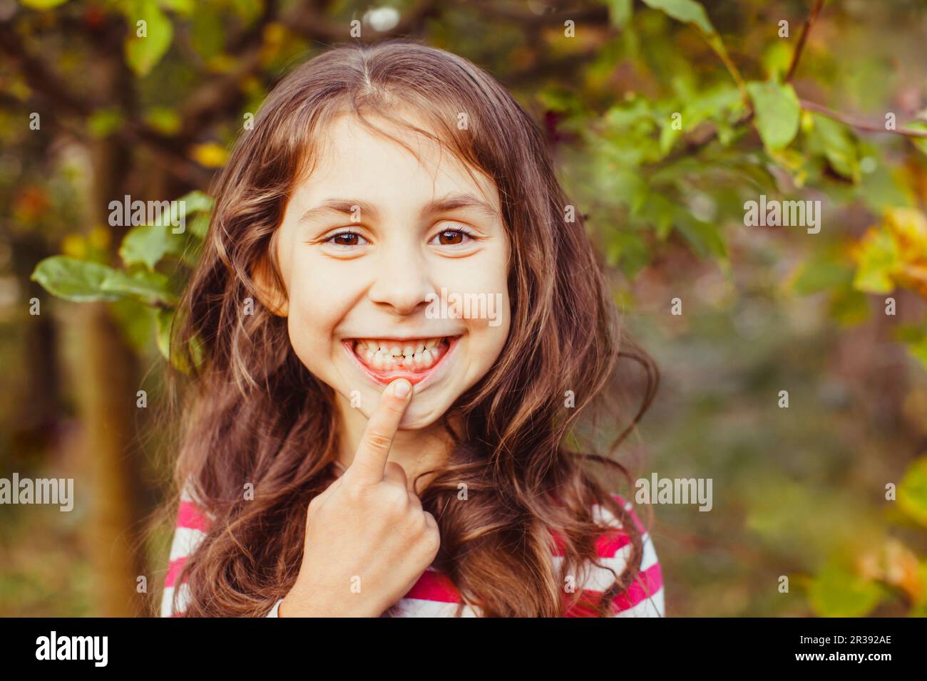 Bambino che indica recentemente eruttato dente anteriore permanente Foto Stock