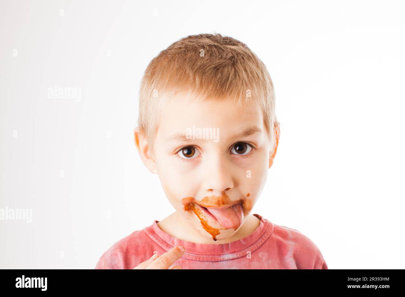 Ritratto del biondo ragazzo con il cioccolato sul suo volto isolato su bianco Foto Stock