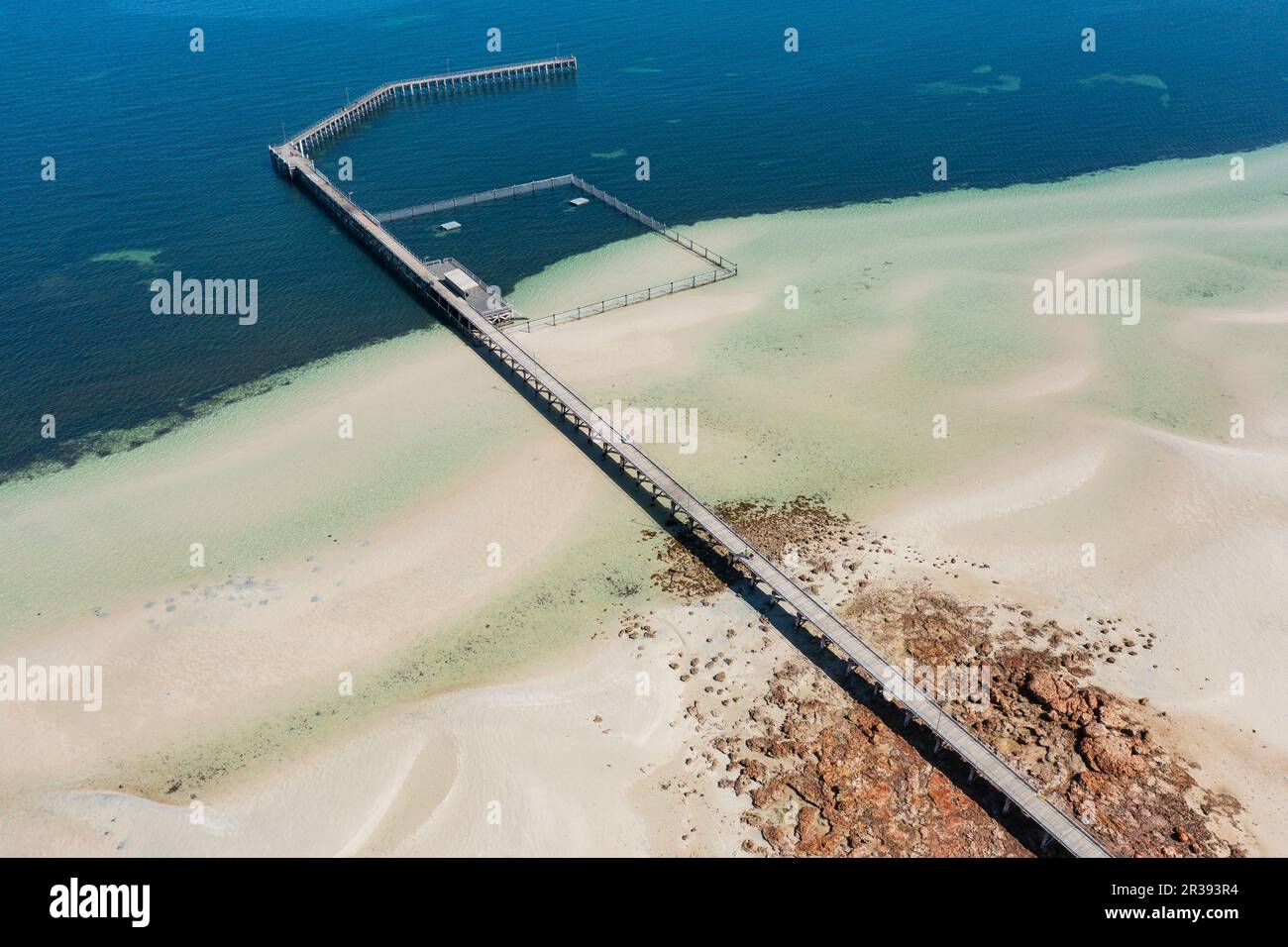 Vista aerea di un lungo e stretto molo che si estende in una tranquilla baia costiera a Moonta Bay, nel sud dell'Australia Foto Stock