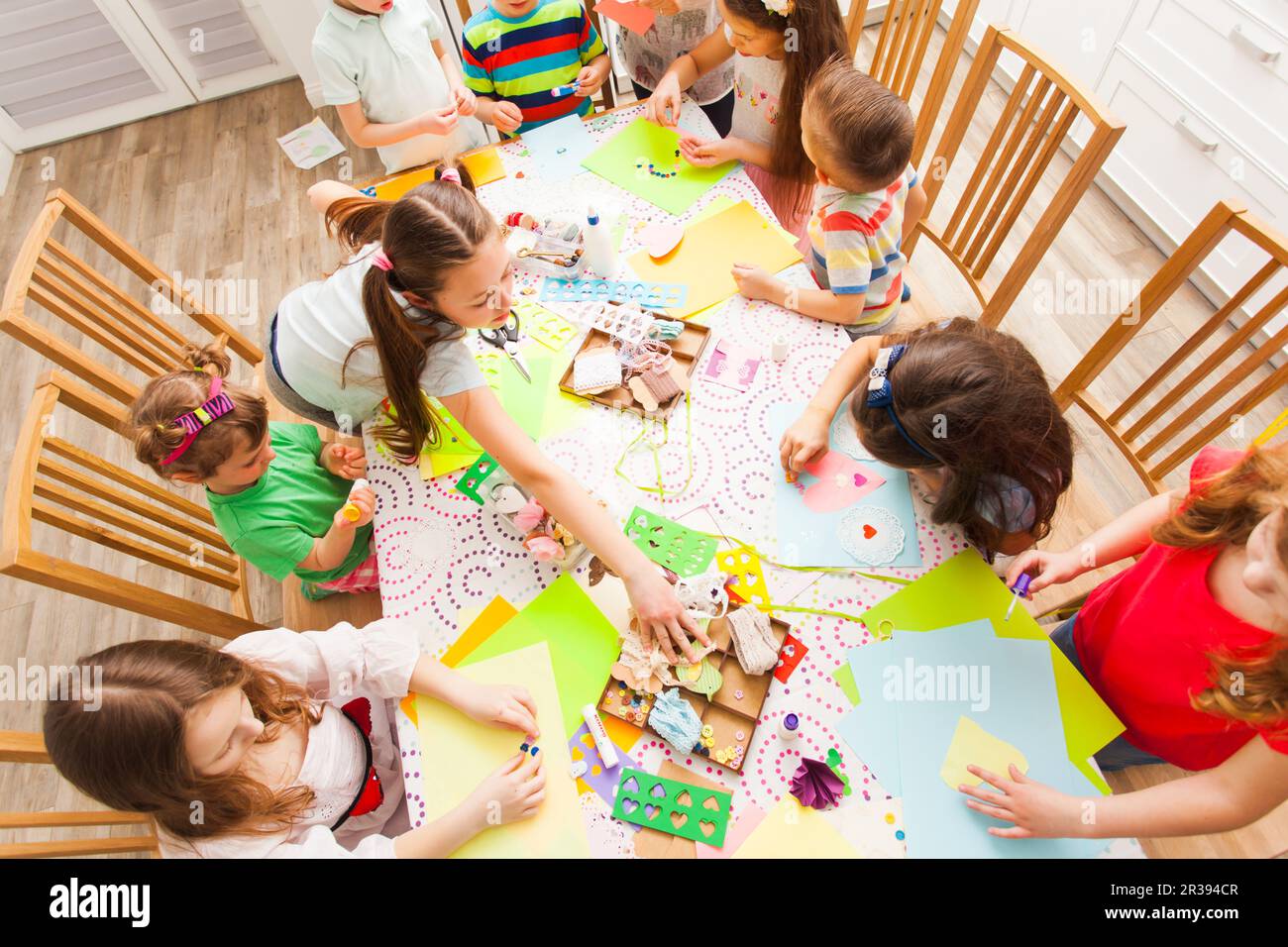 Gruppo di bambini intorno al tavolo facendo cartoline insieme Foto Stock