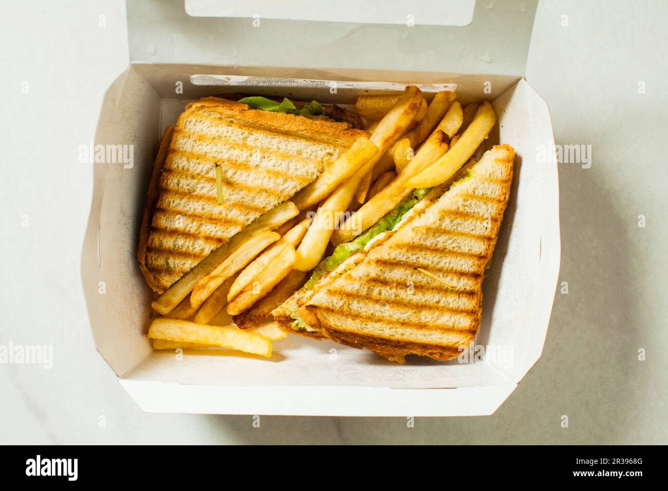 Scatola di carta con sandwich di pollo con patatine fritte Foto Stock