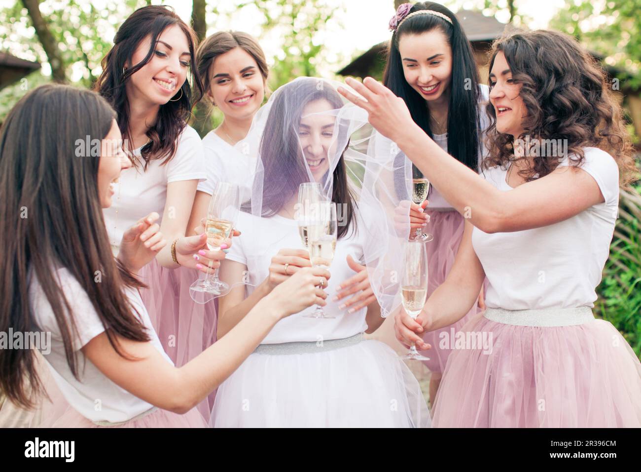 Belle bridesmaids intorno giovane sposa con velo Foto Stock