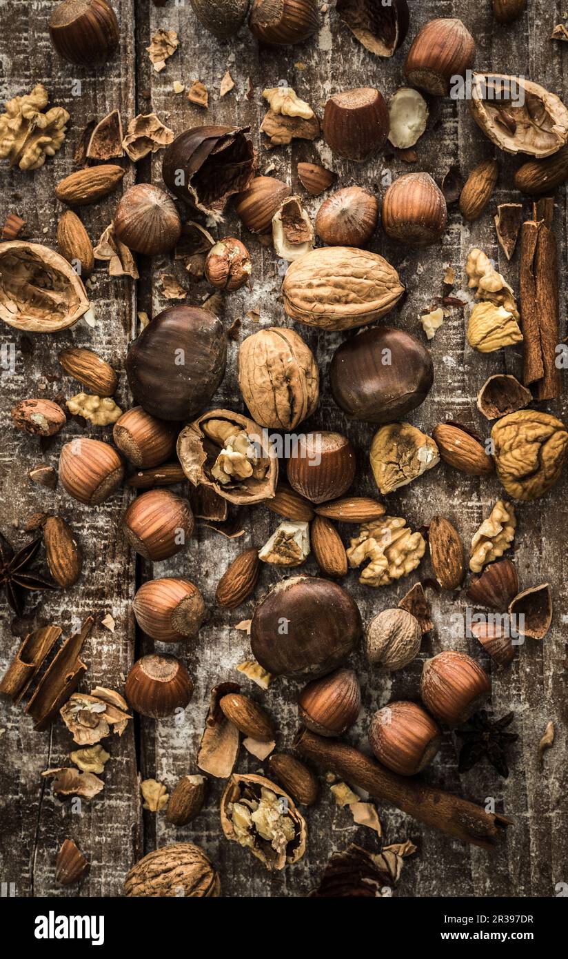 Vari dadi, cannella e anice stellato su una superficie di legno Foto Stock