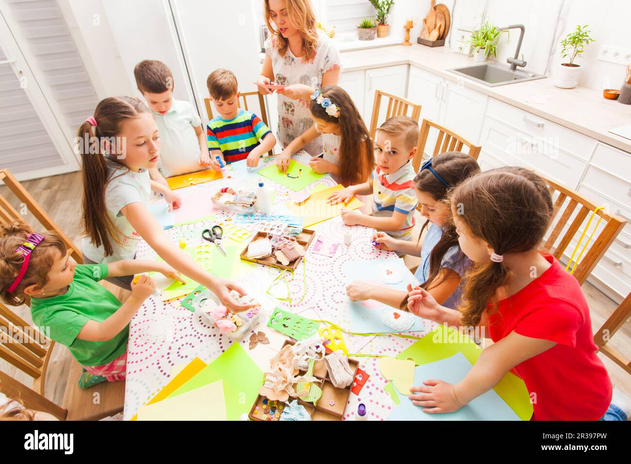 Bambini che lavorano su cartoline con istruttore a casa Foto Stock