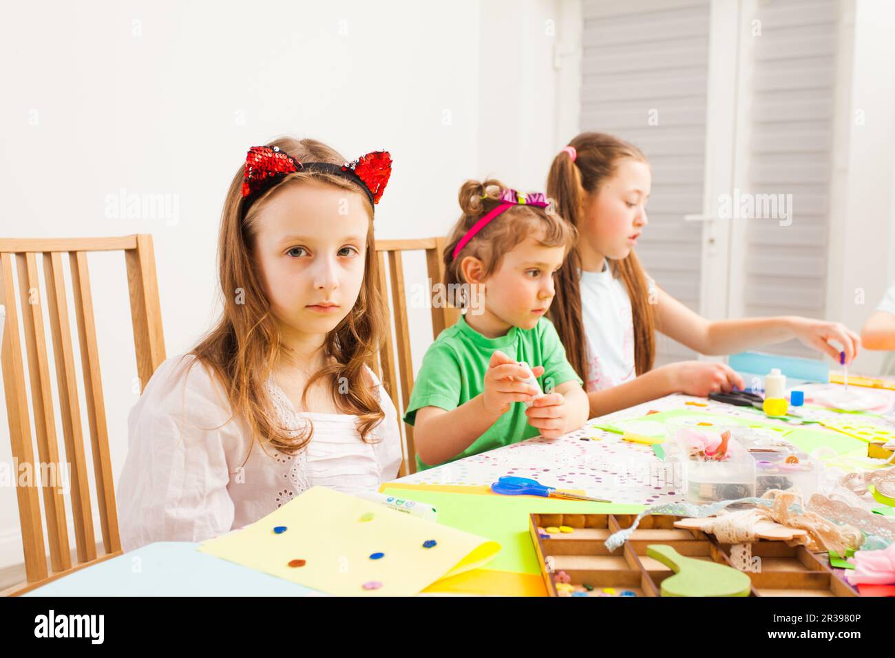 Gruppo di ragazze piccole sedersi e fare belle decorazioni Foto Stock