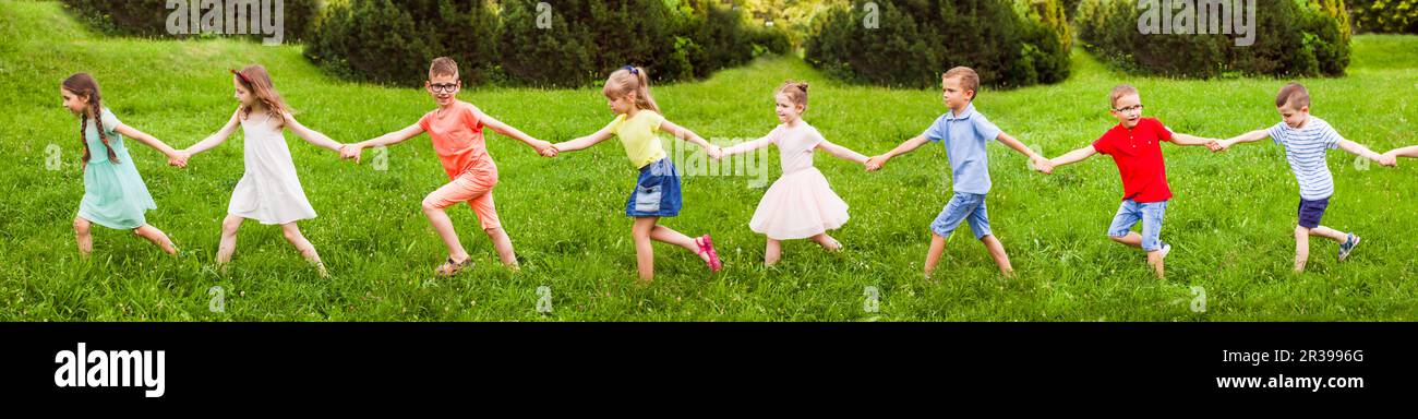 Bambini passeggiate sulla collina di erba tenendo le mani alla giornata di sole Foto Stock