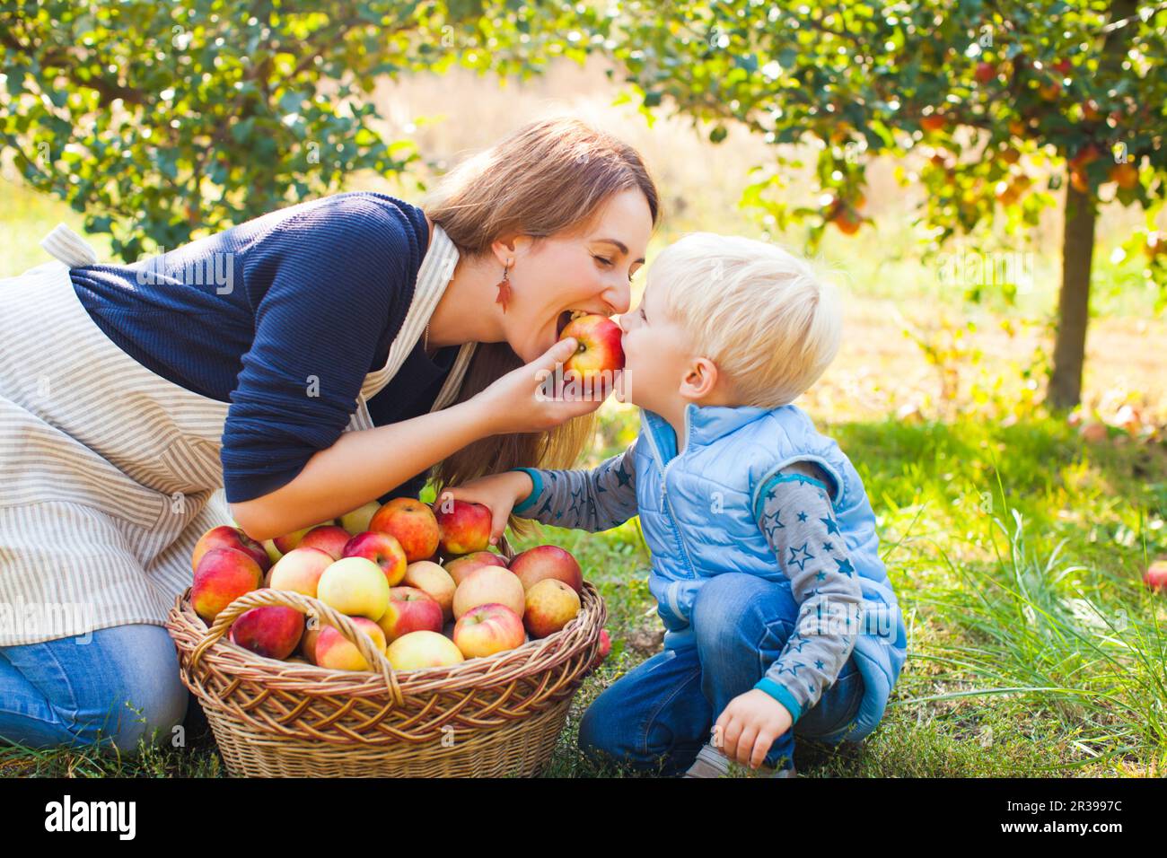 Carino il bambino e la madre di mangiare apple nel giardino. La famiglia felice la raccolta di mele in un agriturismo Foto Stock