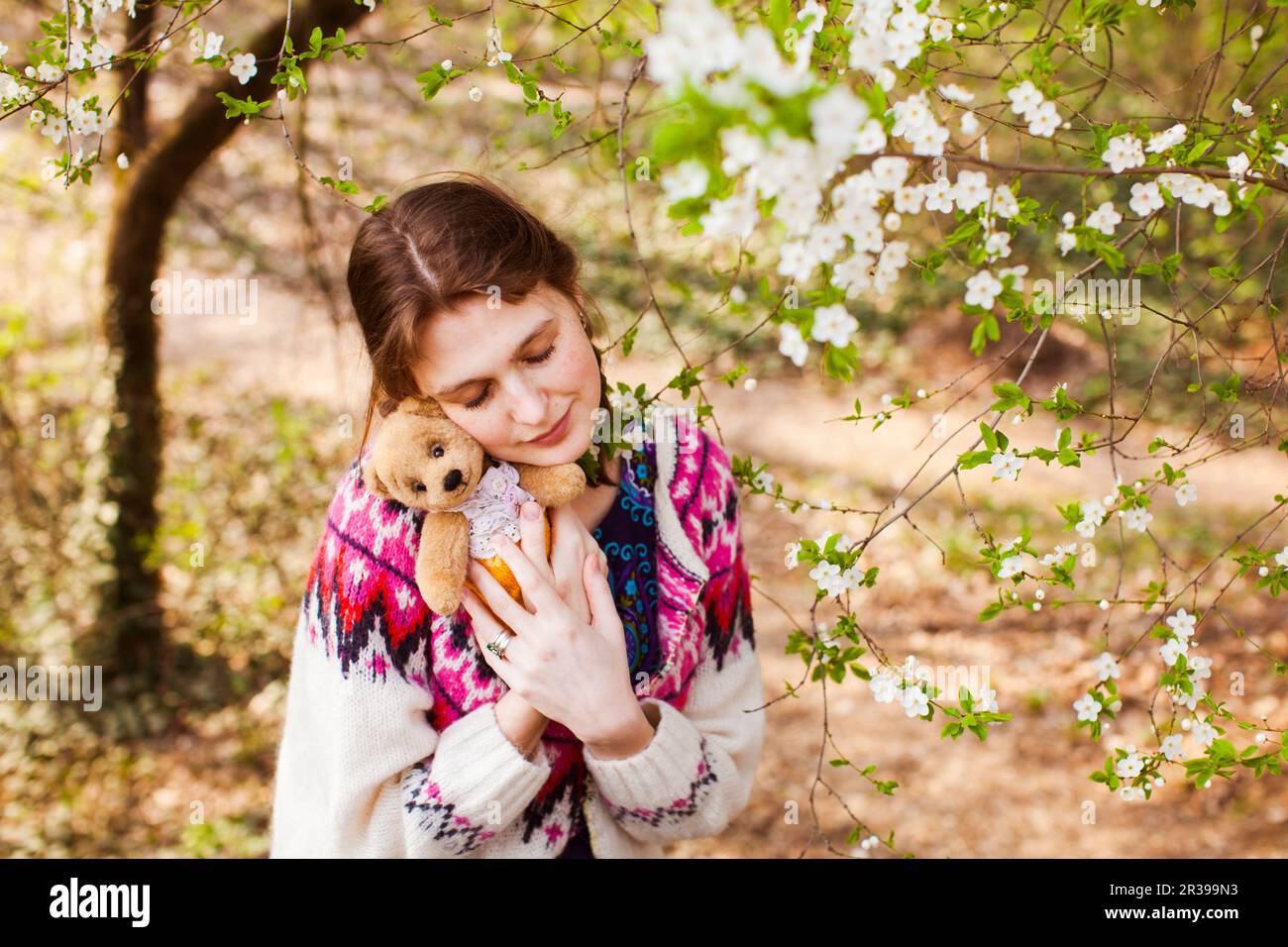 Ragazza triste con toy all'esterno. Infelice bella ragazza adolescente con pig-tail huggs bear toy Foto Stock