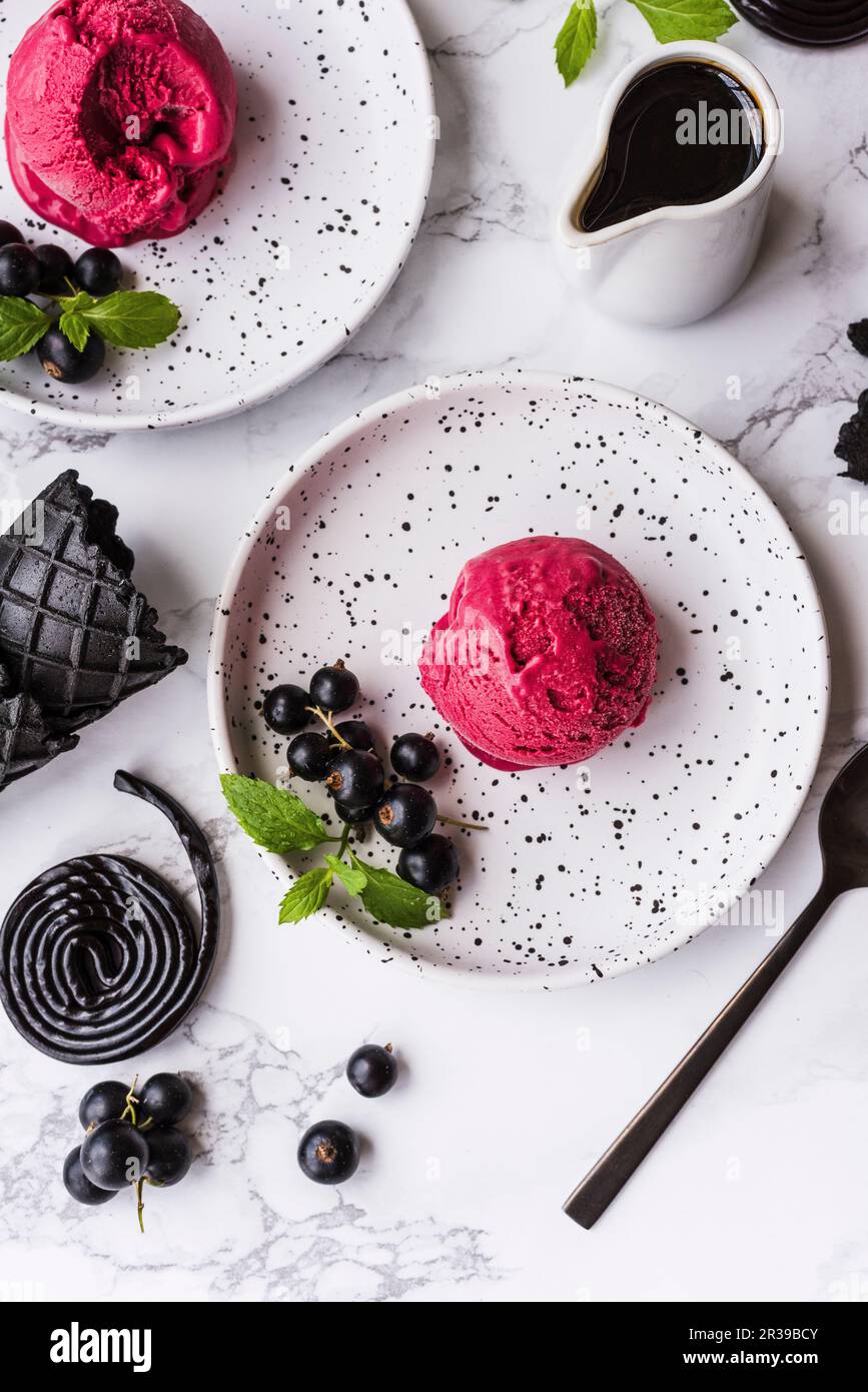 Gelato alla liquirizia con ribes neri su piatti da dessert bianchi Foto Stock