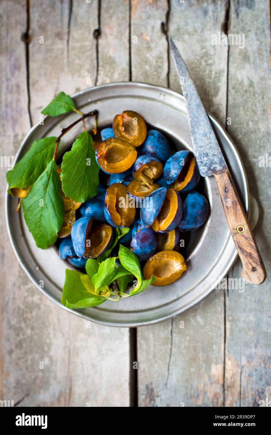 Damson con foglie su un piatto di peltro Foto Stock