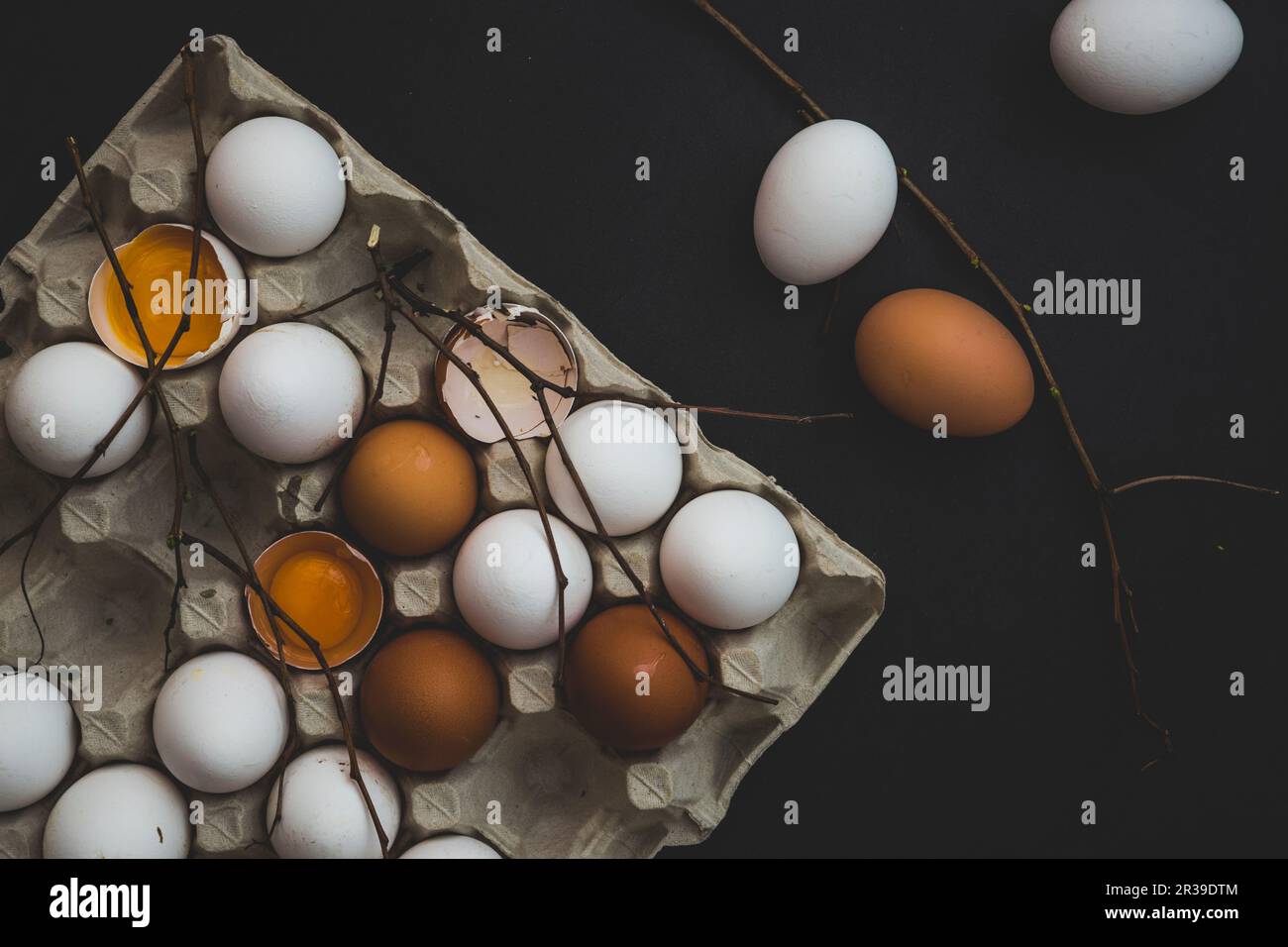 Una scatola di uova con uova di gallina bianche e marroni, intere e spaccate Foto Stock