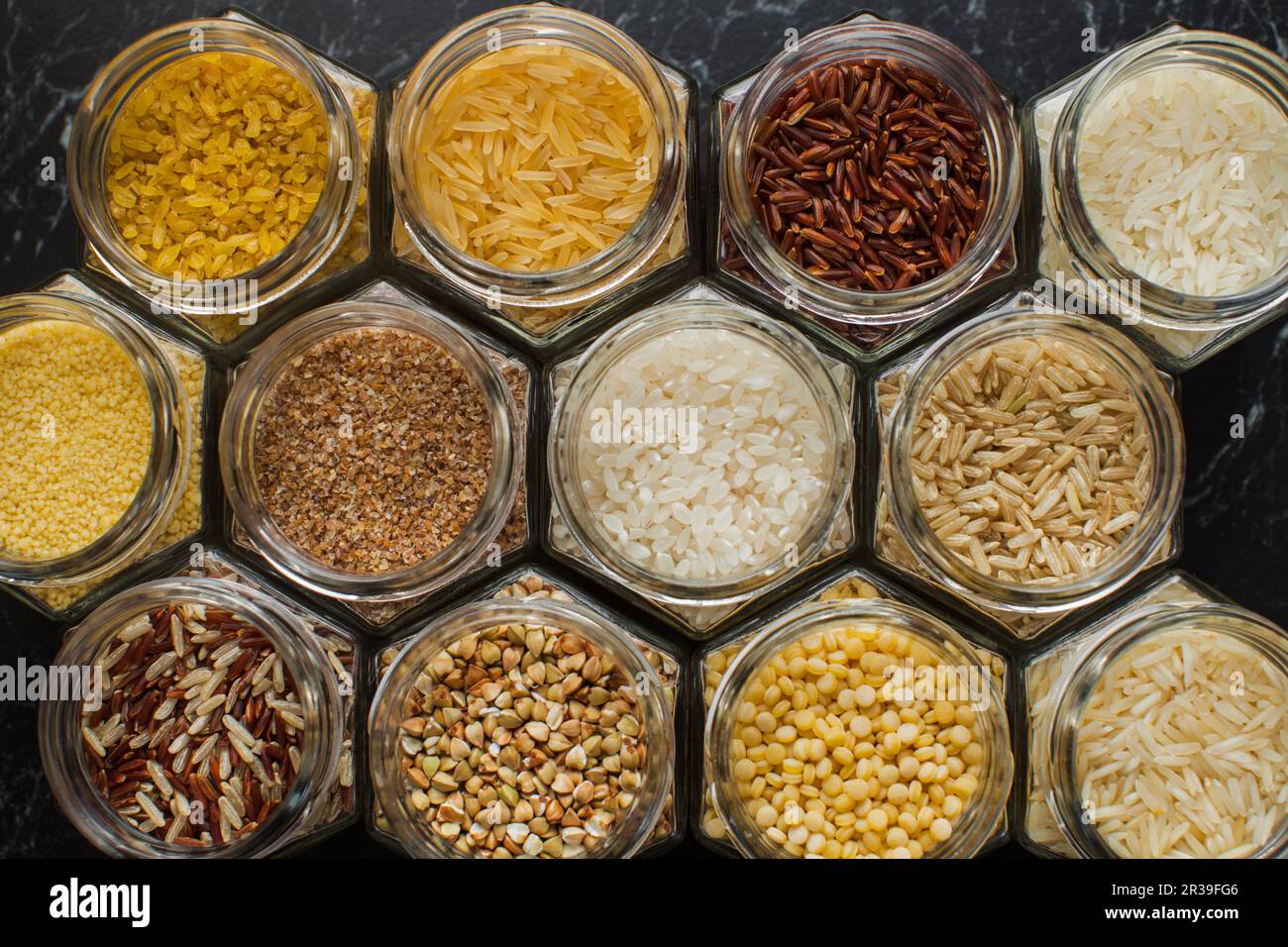 Vista dall'alto di vasi di vetro con vari cereali, riso, couscous, bulgur e grano saraceno. Foto Stock