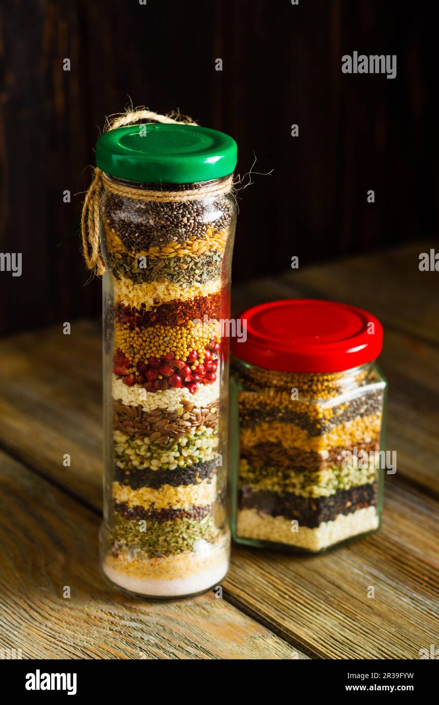 Vasetti di vetro con erbe e spezie colorate. Bottiglie per la decorazione della cucina. Foto Stock