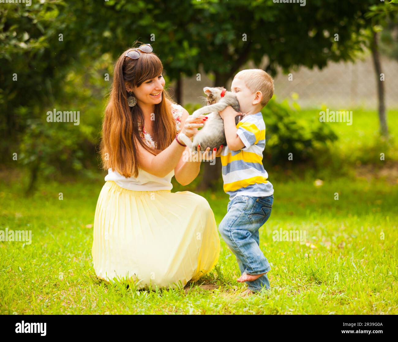 Buona famiglia che gioca con un gatto su erba verde in giardino Foto Stock