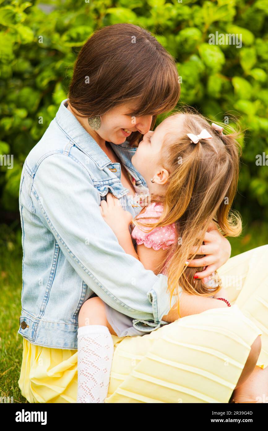 Madre felice e figlia abbracciando e baciare nel parco estivo. Foto Stock
