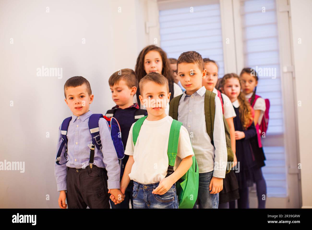 Gruppo di ragazzi delle scuole elementari con zaini nel corridoio scolastico. Ritorno a scuola Foto Stock