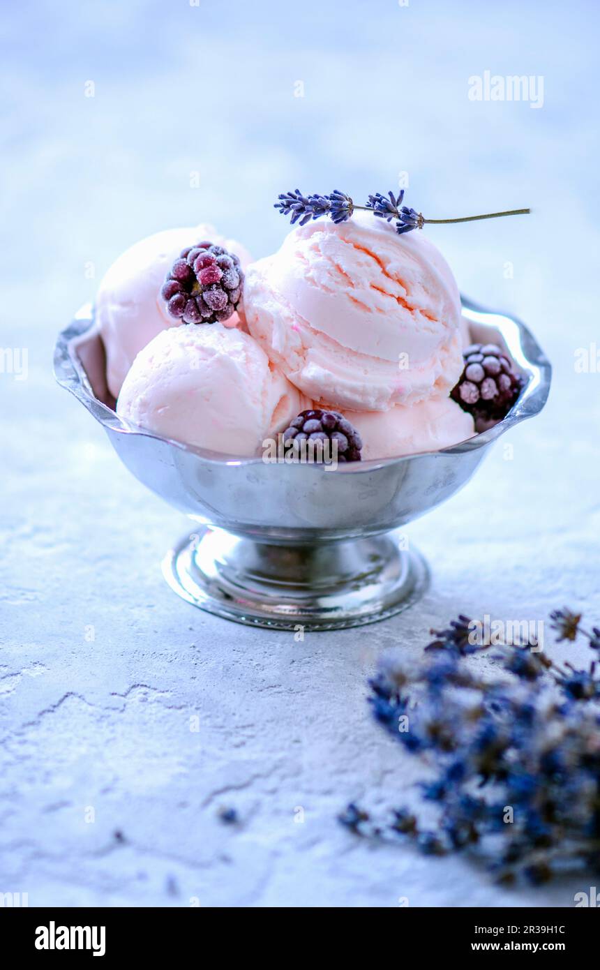 Palle di gelato rosa in ciotole di gelato con more e lavanda Foto Stock