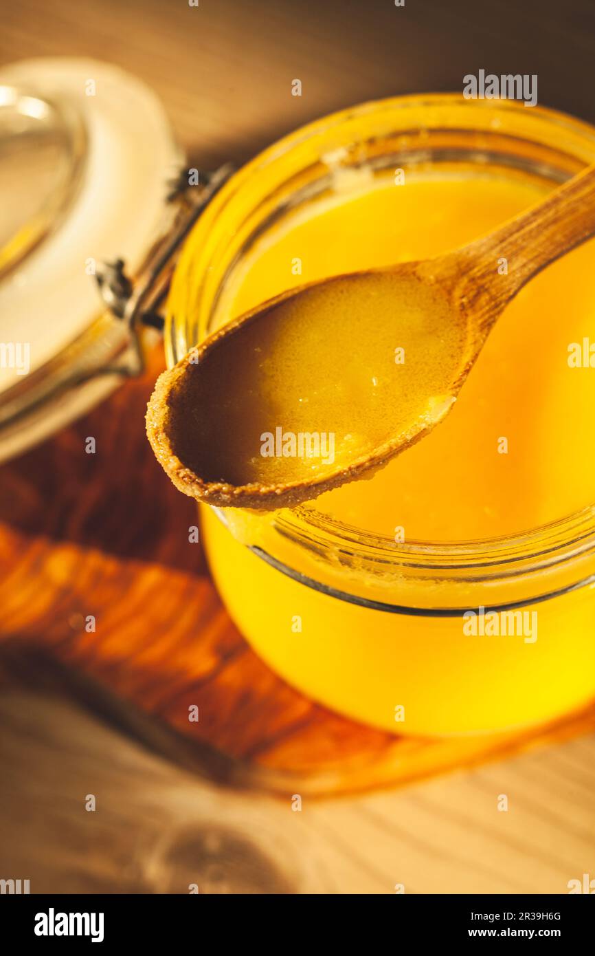 Cucchiaio di legno con ghee - burro chiarificato in vaso Foto Stock