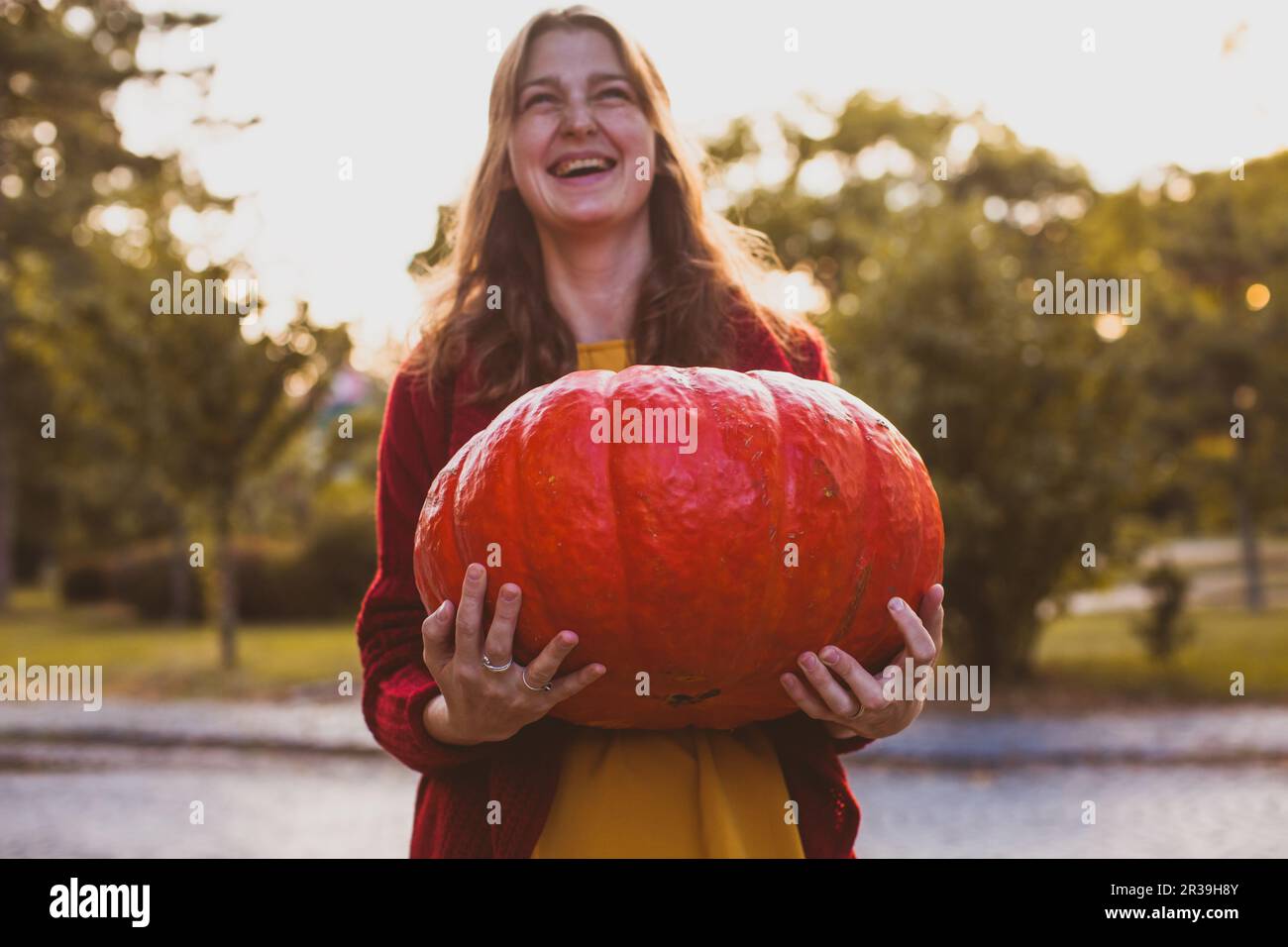 Donna con zucca gigante nelle mani, festeggiando felice giorno del Ringraziamento Foto Stock