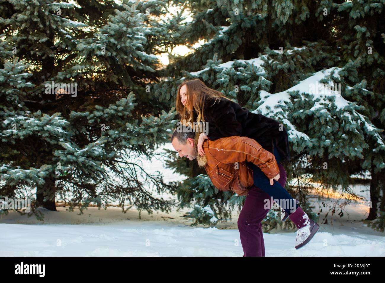 Felice uomo che tiene la moglie in mano nel parco invernale. Buon San Valentino Foto Stock