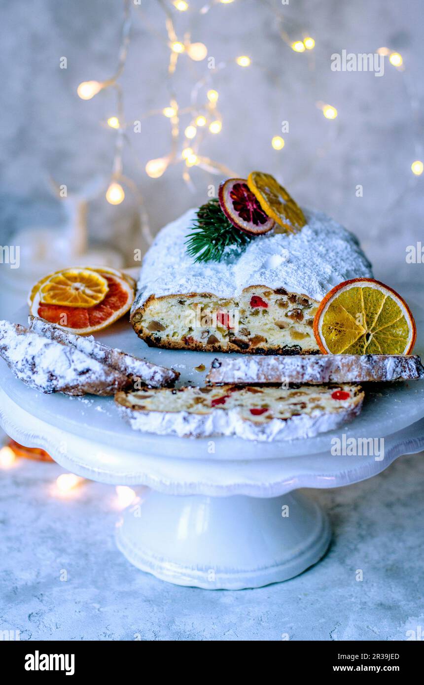 Christmas Stollen su uno stand bianco decorato con fette secche di arancio e ghirlanda Foto Stock