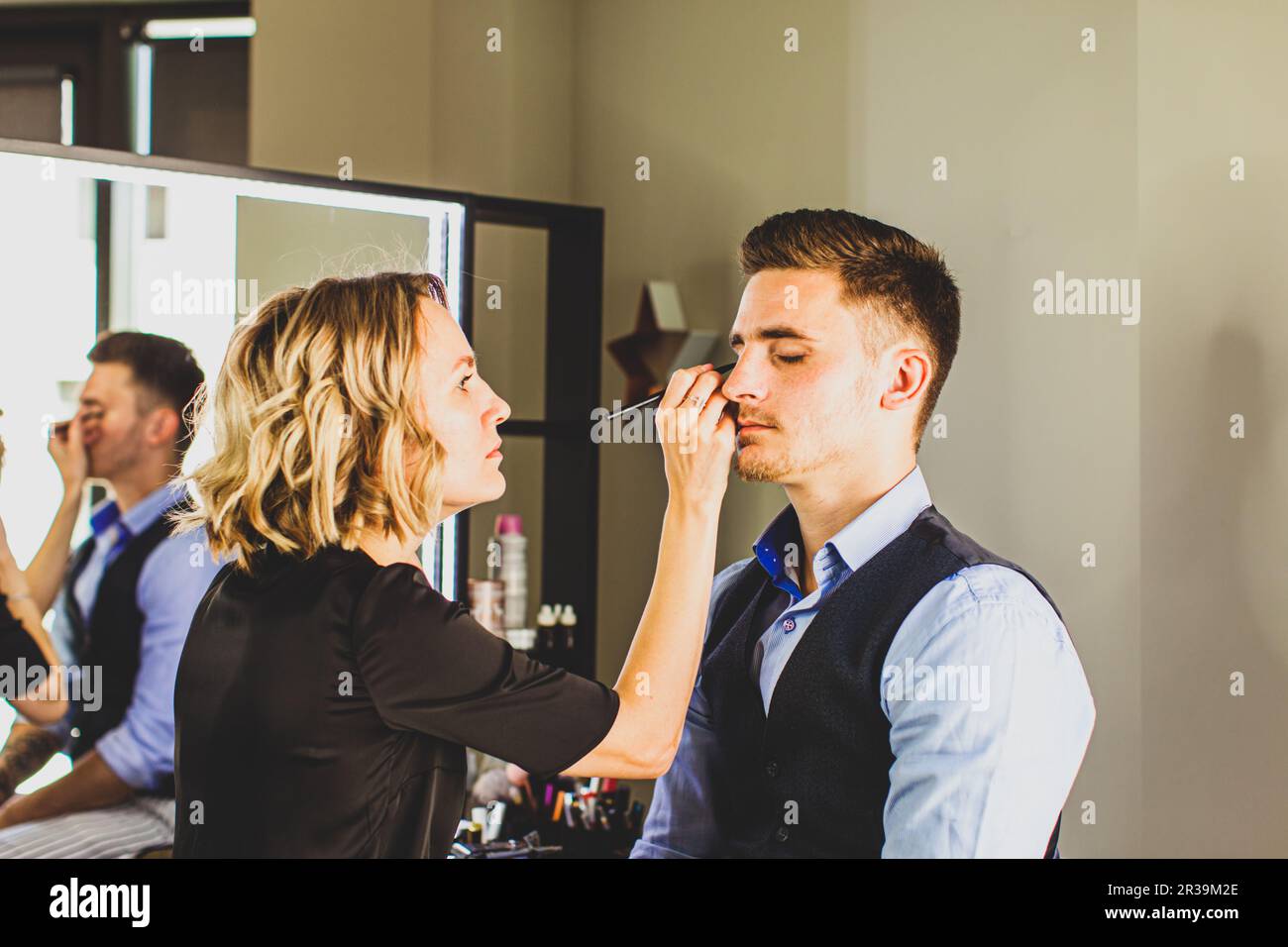 Makeup artista fare trucco professionale per il giovane uomo. Foto Stock