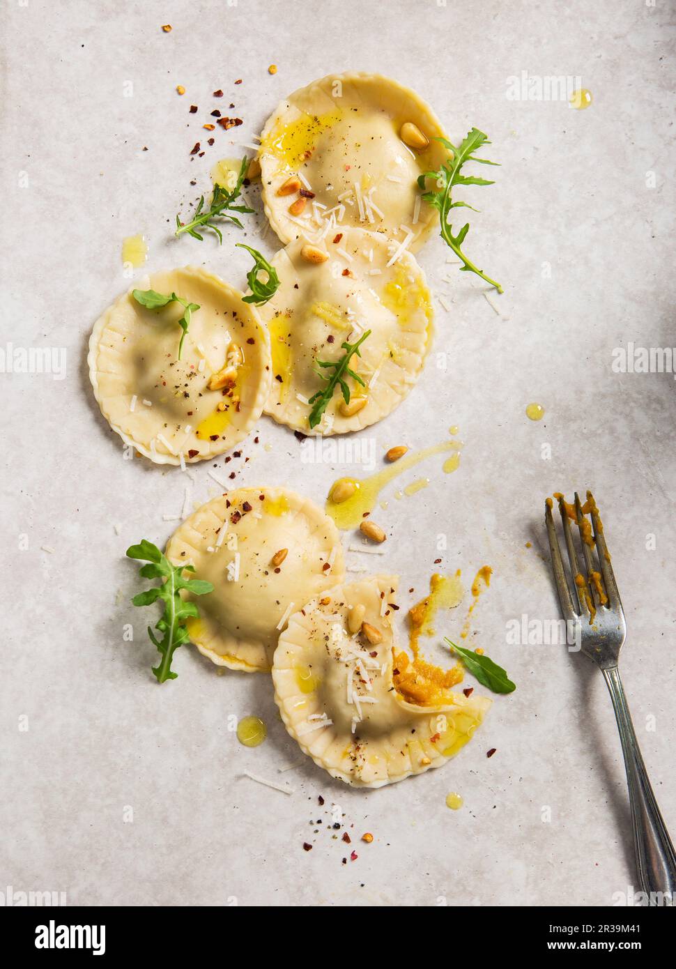 Tortelloni di ravioli di zucca fatti in casa con pinoli, olio d'oliva, rucola e peperoncino Foto Stock