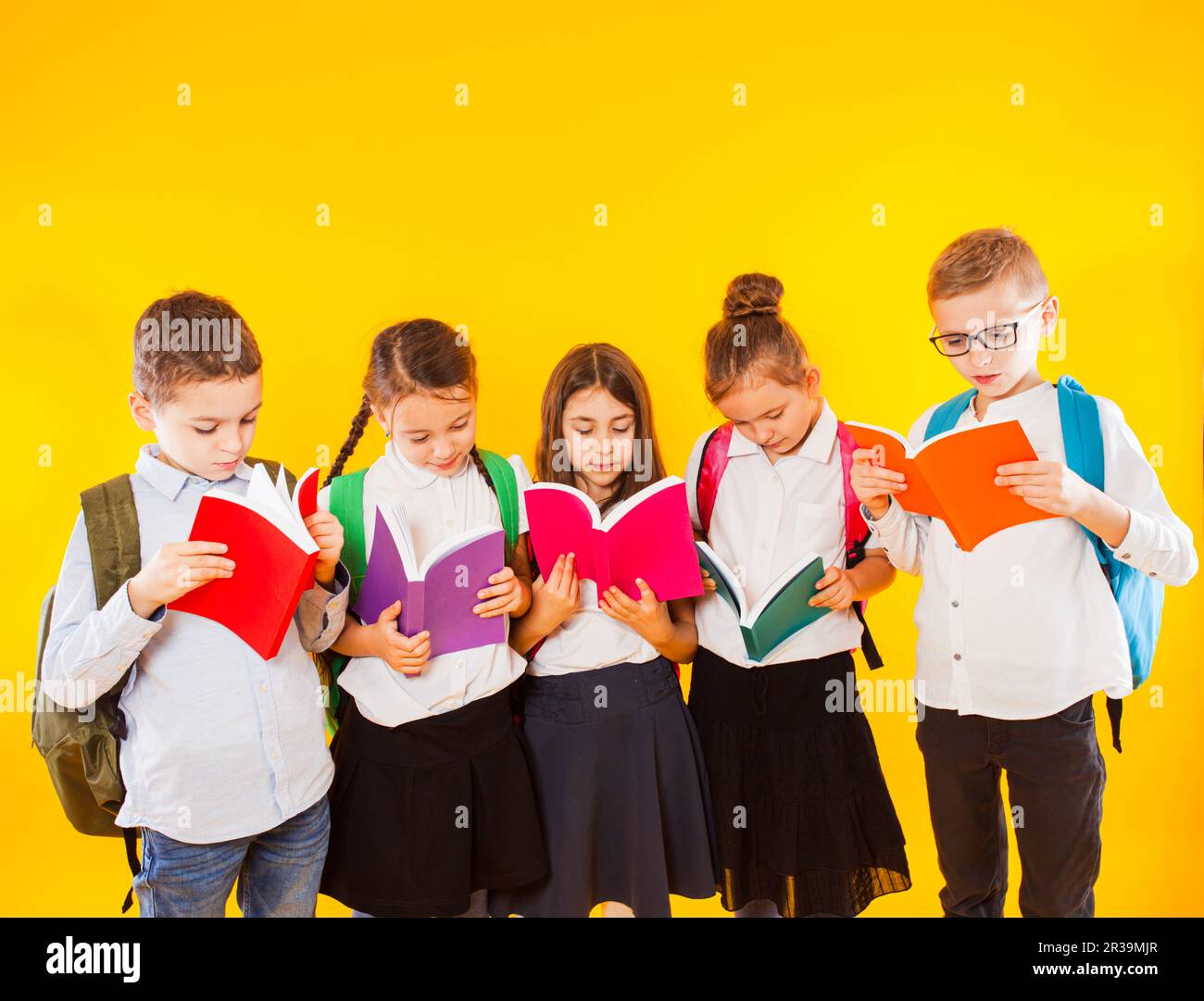 Gruppo di compagni di classe lettura libro su sfondo giallo. Foto Stock