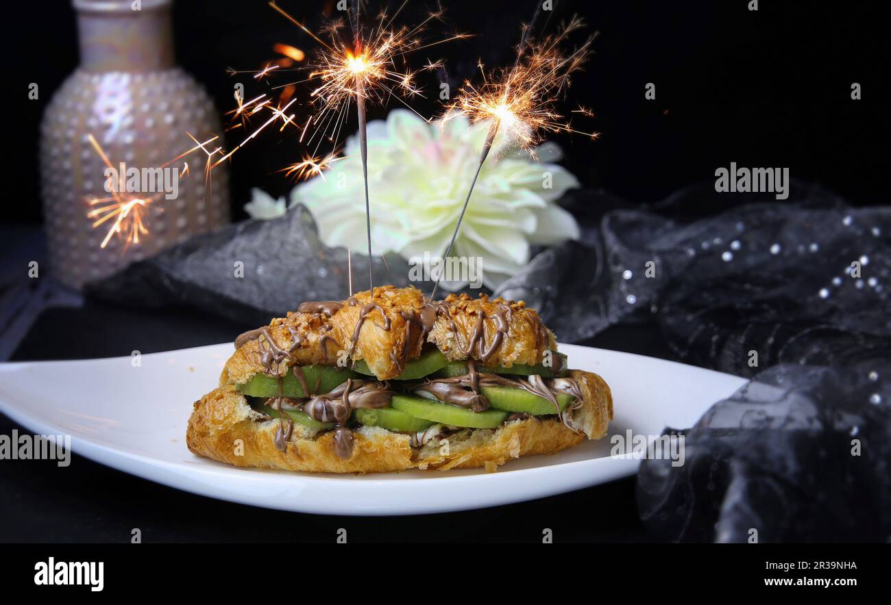 Un croissant con kiwi e crema di cioccolato decorato con scintillanti Foto Stock