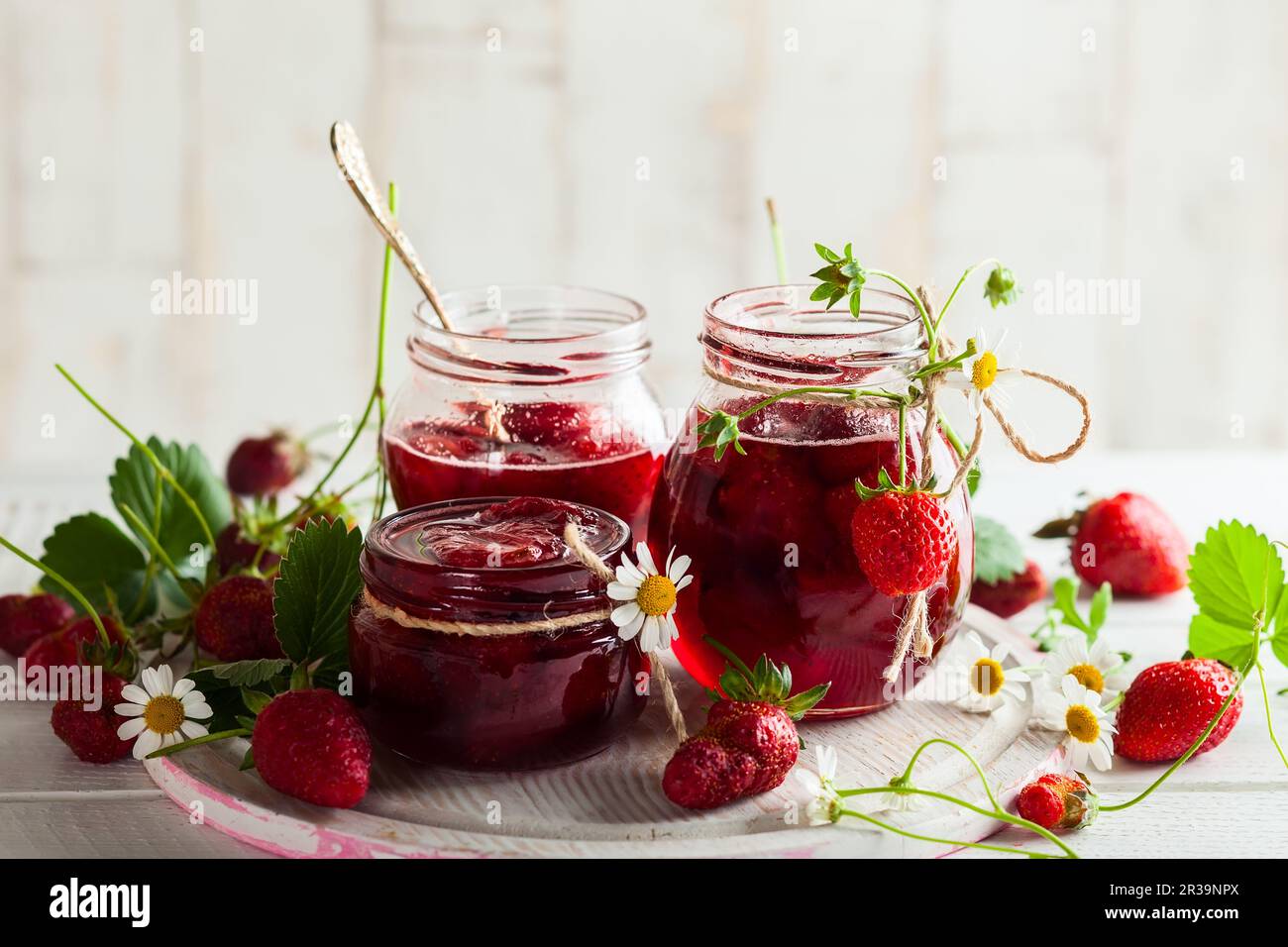 Marmellata di fragole fatta in casa in vasetti di vetro su tavola di legno in stile rustico. Cibo sano per la colazione Foto Stock