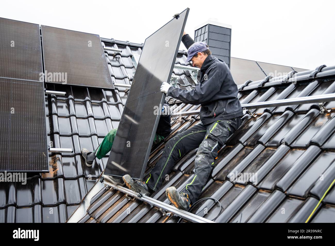 Team di tecnici che installano pannelli solari sul tetto di una casa Foto Stock