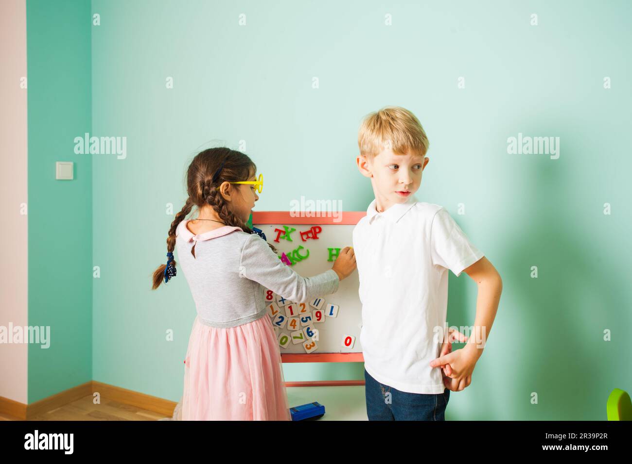 I bambini giocano e imparano gli alfabeti magnetici a bordo in camera Foto Stock