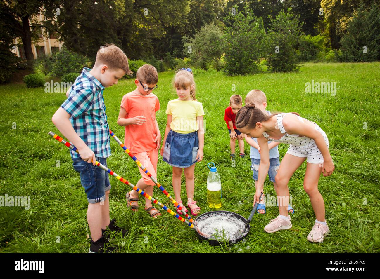 Piccoli amici allenarsi per fare grandi bolle di sapone su un prato Foto Stock