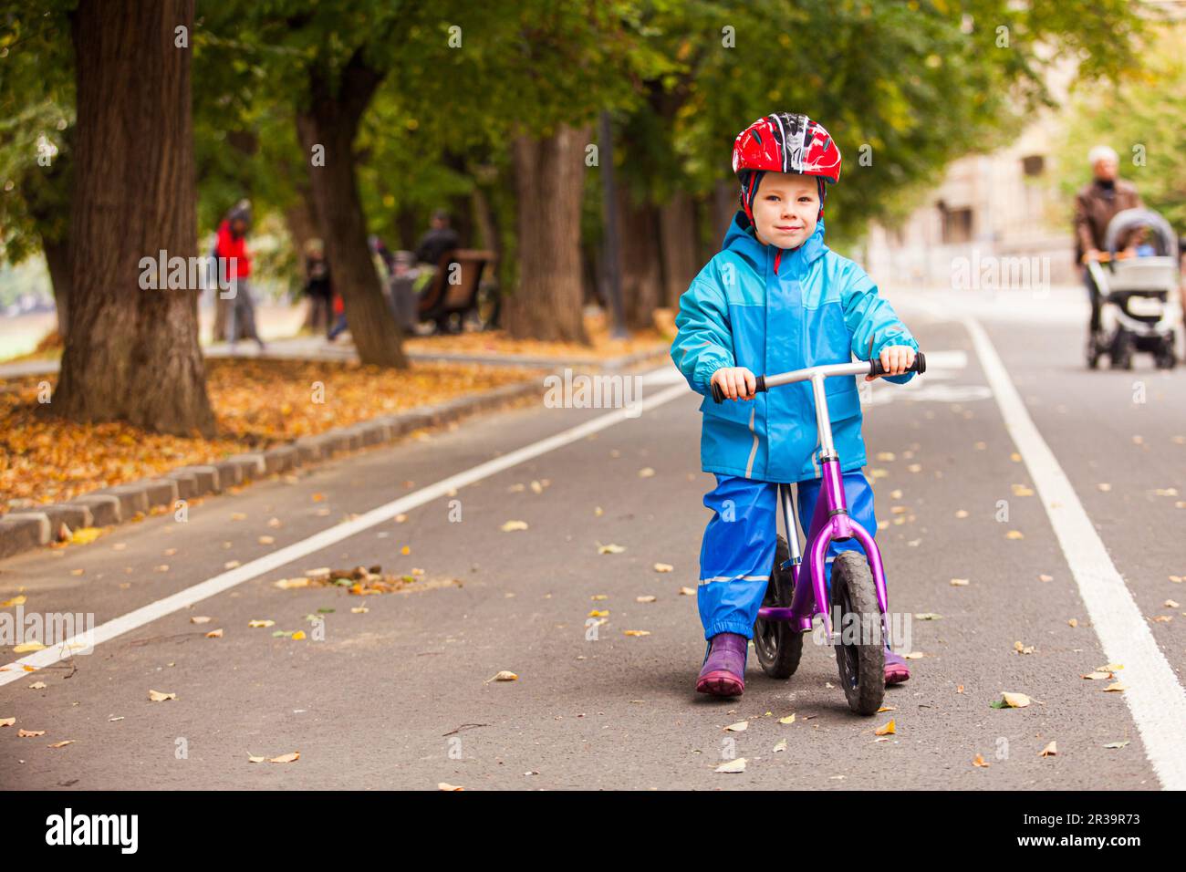 Bambino in abiti autunnali blu sulla sua bicicletta Foto Stock