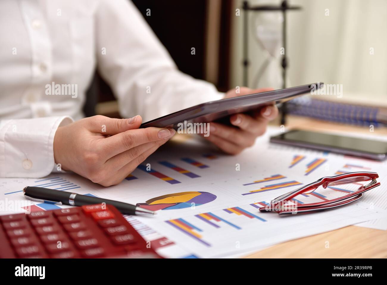 Donna d'affari in ufficio con un tablet digitale. Grafici di reddito e grafici a tabella. Foto Stock
