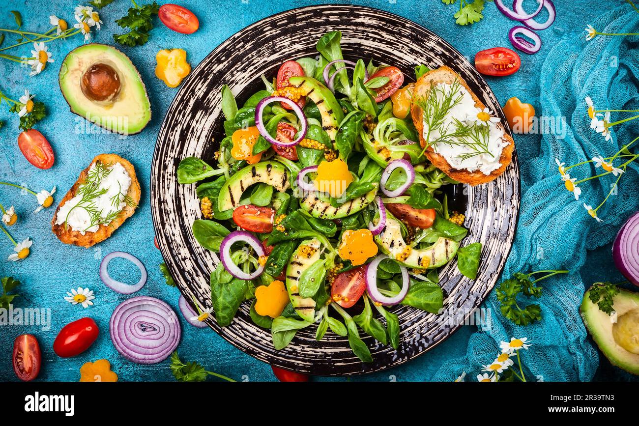 Per mangiare sano: Insalata con avocado alla griglia, verdure fresche, toast con formaggio morbido e condimento di senape. Vista dall'alto Foto Stock