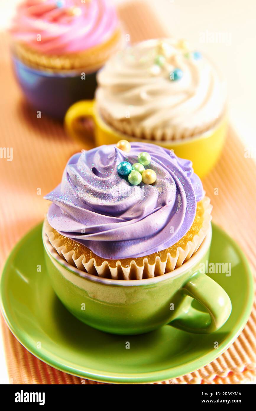 Cupcake decorati con crema di burro colorata servita in tazzine da tè  colorate Foto stock - Alamy