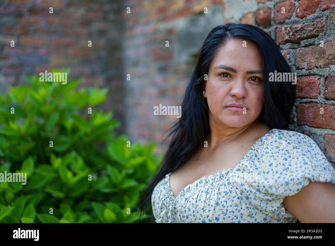 Ritratto di una bellissima donna latina adulta che posa su uno sfondo di mattoni Foto Stock