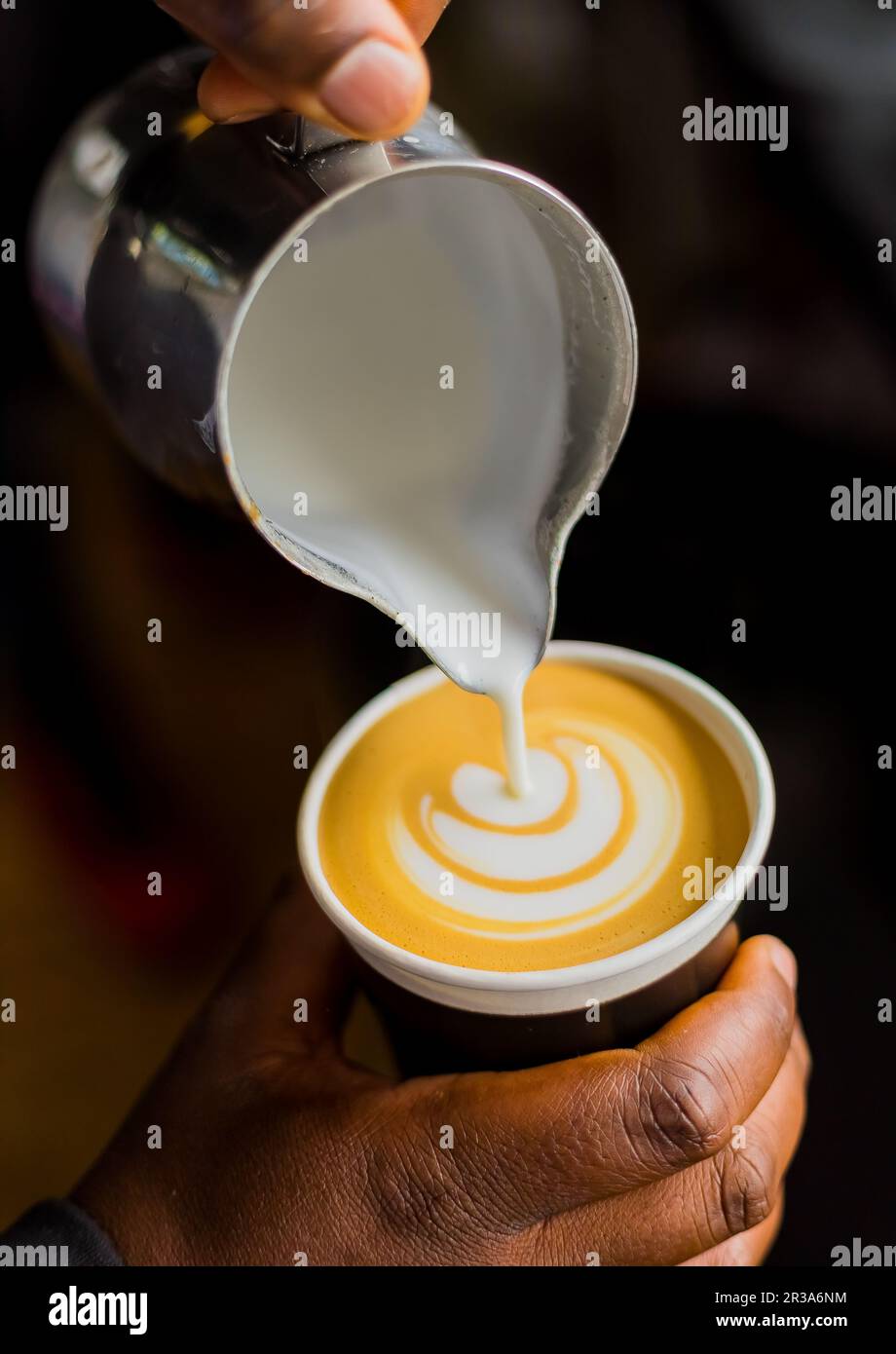 Caffè africani Barista versando una foglia forma con schiuma di latte in un take away cup Foto Stock