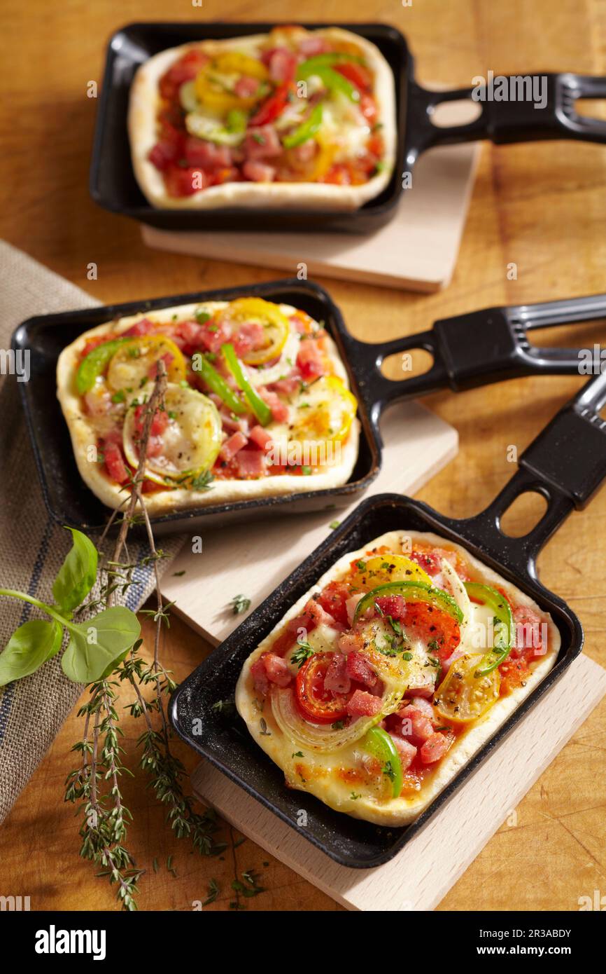 Mini pizze di raclette al forno con formaggio e verdure Foto Stock