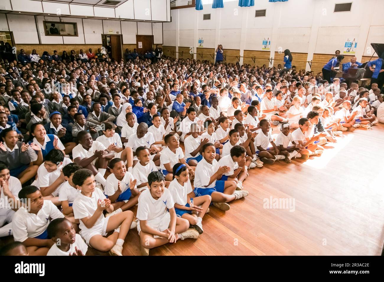 Giovani bambini di scuola diversi seduti sul pavimento in un'assemblea mattutina Foto Stock